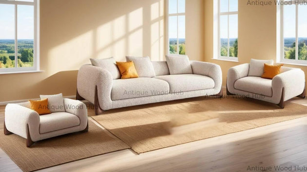 White sofa set with orange cushions in a bright room with large windows.