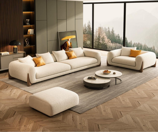 Modern living room with beige sofa, ottoman, and coffee table on a wooden floor.