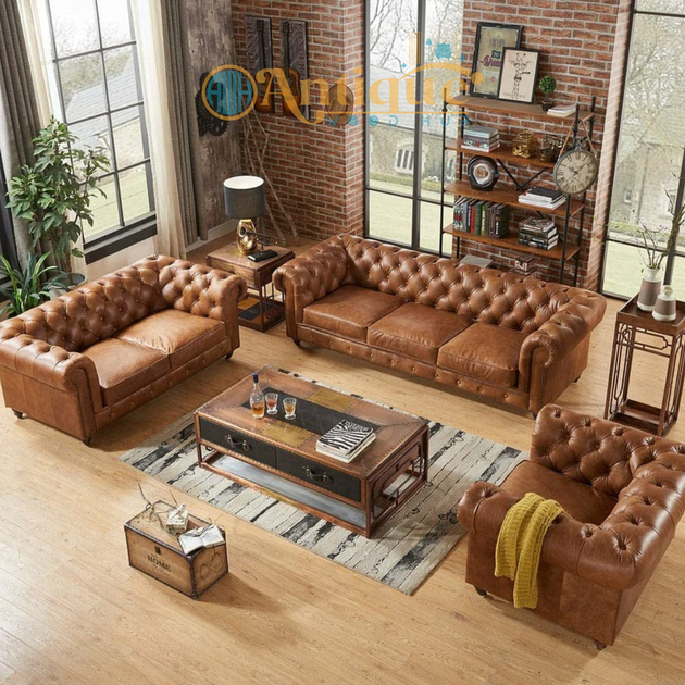 Brown leather sofa set in a living room with brick walls and large windows.