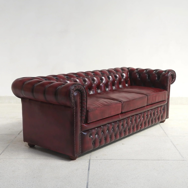 Maroon leather sofa with tufted backrest on a light gray floor and white background