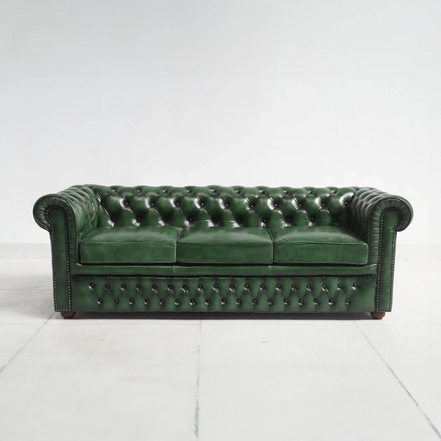 Green leather sofa with tufted backrest on a white background