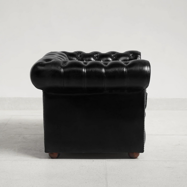 Black leather armchair with tufted backrest on a white background