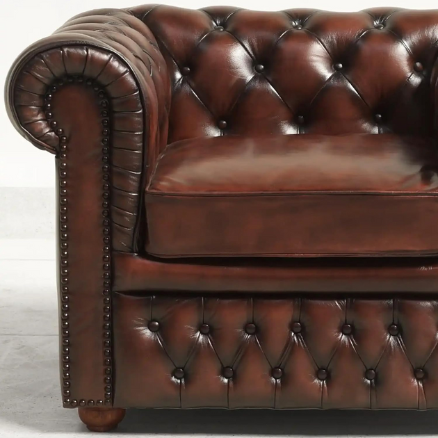 Brown leather Chesterfield sofa with tufted backrest on a light gray background