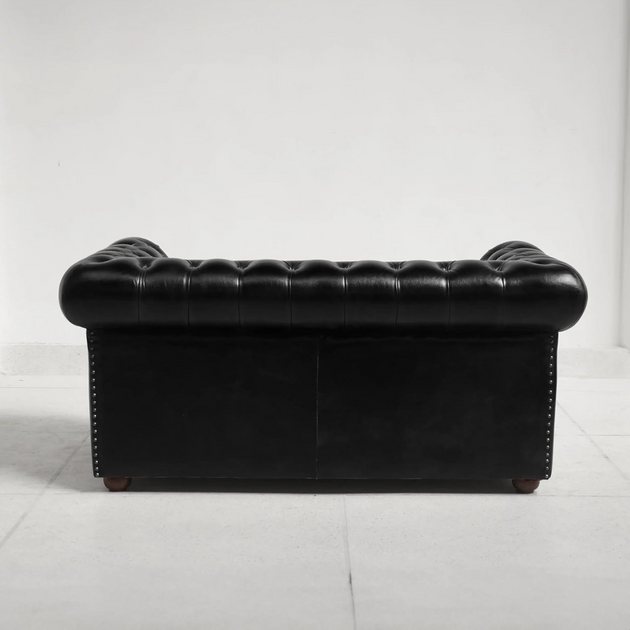 Black leather sofa on a white floor with a white wall background