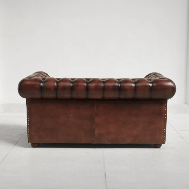Brown leather sofa with tufted backrest on a white background