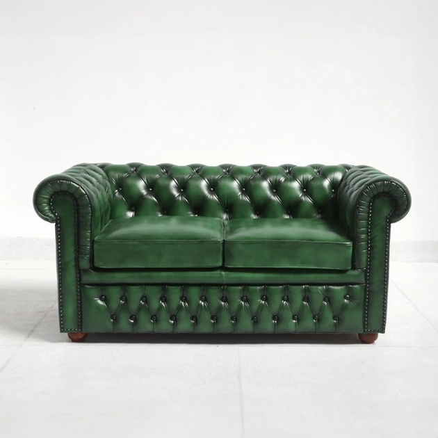 Green leather sofa with tufted backrest on a white background