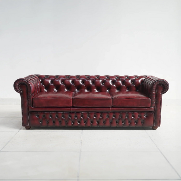 Red leather sofa with tufted backrest on a white background