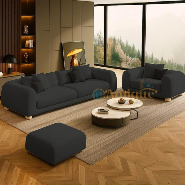 Modern living room with dark gray sofa, ottoman, and coffee table on a wooden floor.