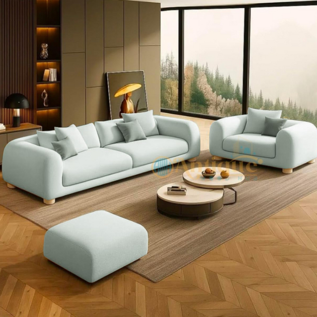 Modern living room with light gray sofa, ottoman, and coffee table on a wooden floor.