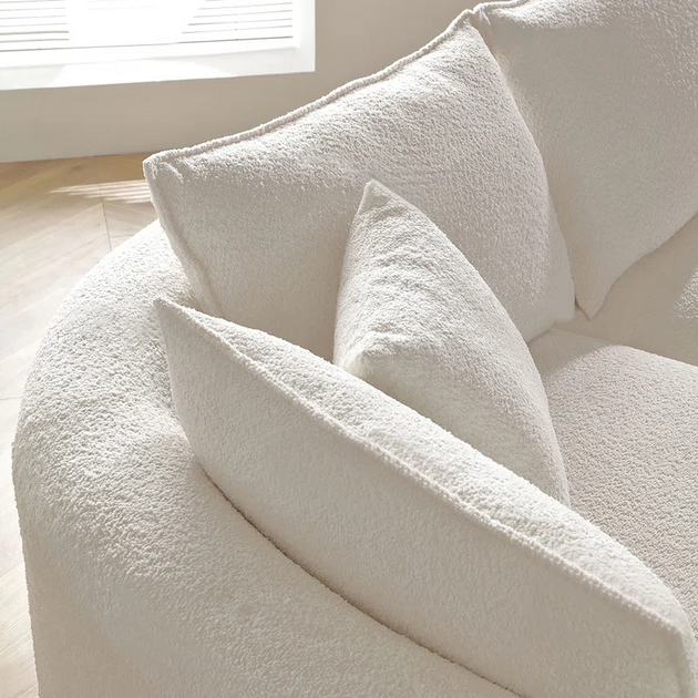 Close-up detail of three plush back cushions on a white or cream-colored boucle sectional sofa, highlighting the texture of the fabric.