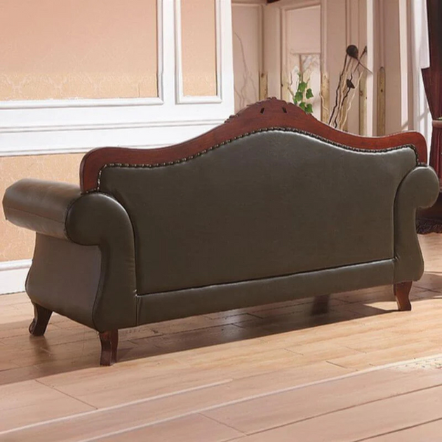 Green leather sofa with wooden armrests in a room with light-colored walls and wooden floor.