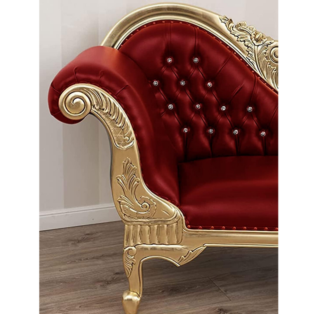 Red velvet sofa with gold frame and decorative elements on a wooden floor.