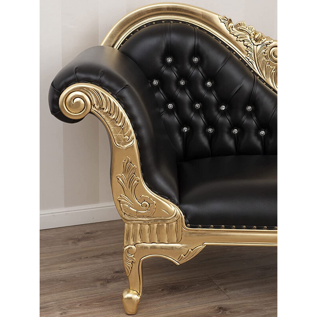 Black leather sofa with gold decorative armrests on a wooden floor.