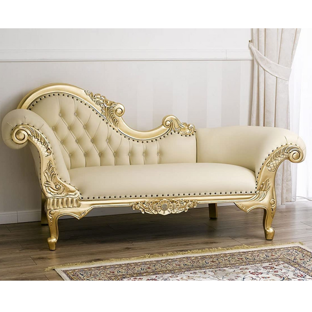 Decorative chaise lounge with gold accents in a room with white walls and wooden floor.