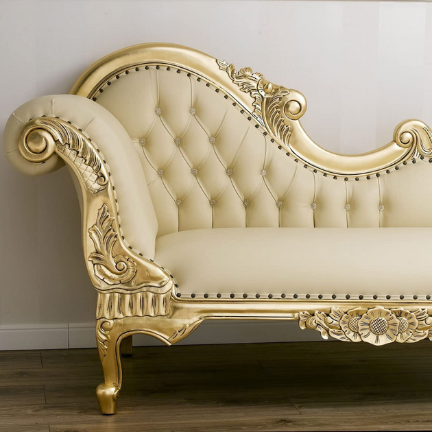 Decorative cream sofa with gold accents against a white wall.