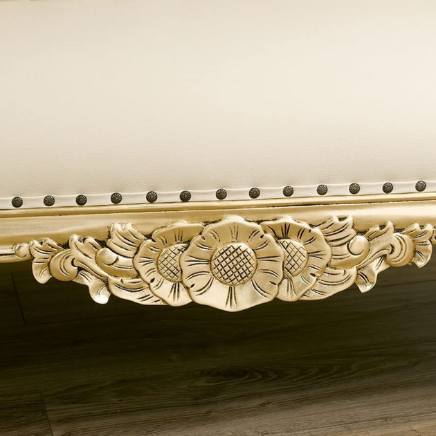 Decorative wooden molding with floral carvings and nailhead trim on a neutral background