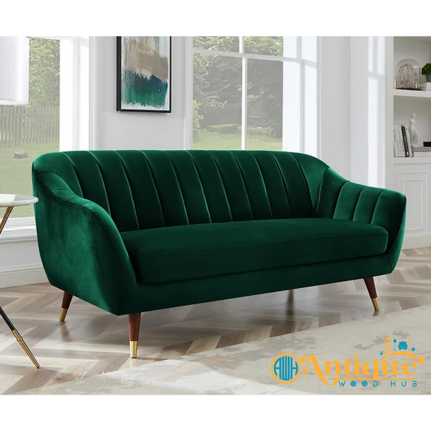 Green velvet sofa in a room with large windows and a visible brand logo.